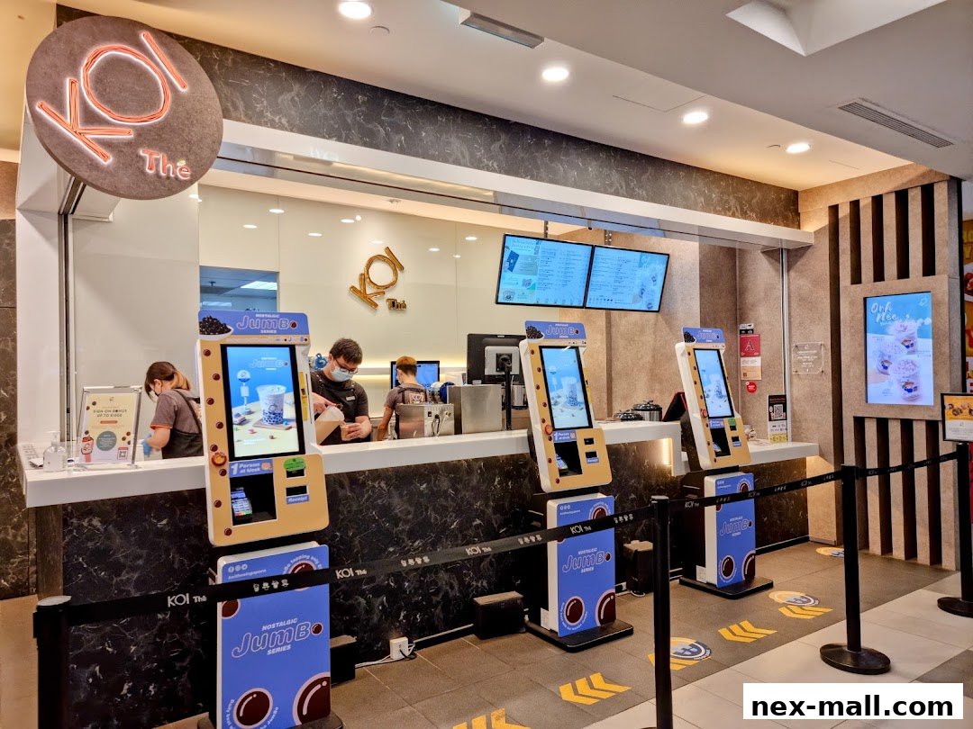 KOI Thé NEX shop with self-order kiosks and staff preparing drinks.