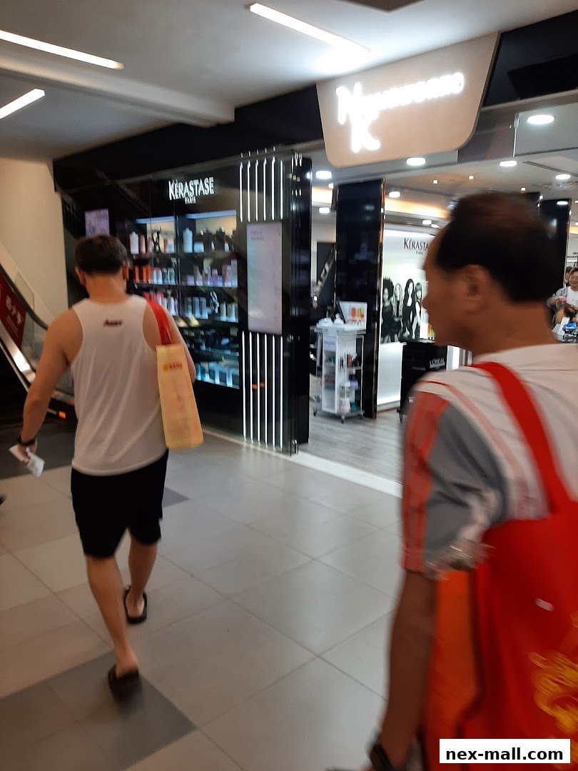 People walking past a hair salon with products displayed.