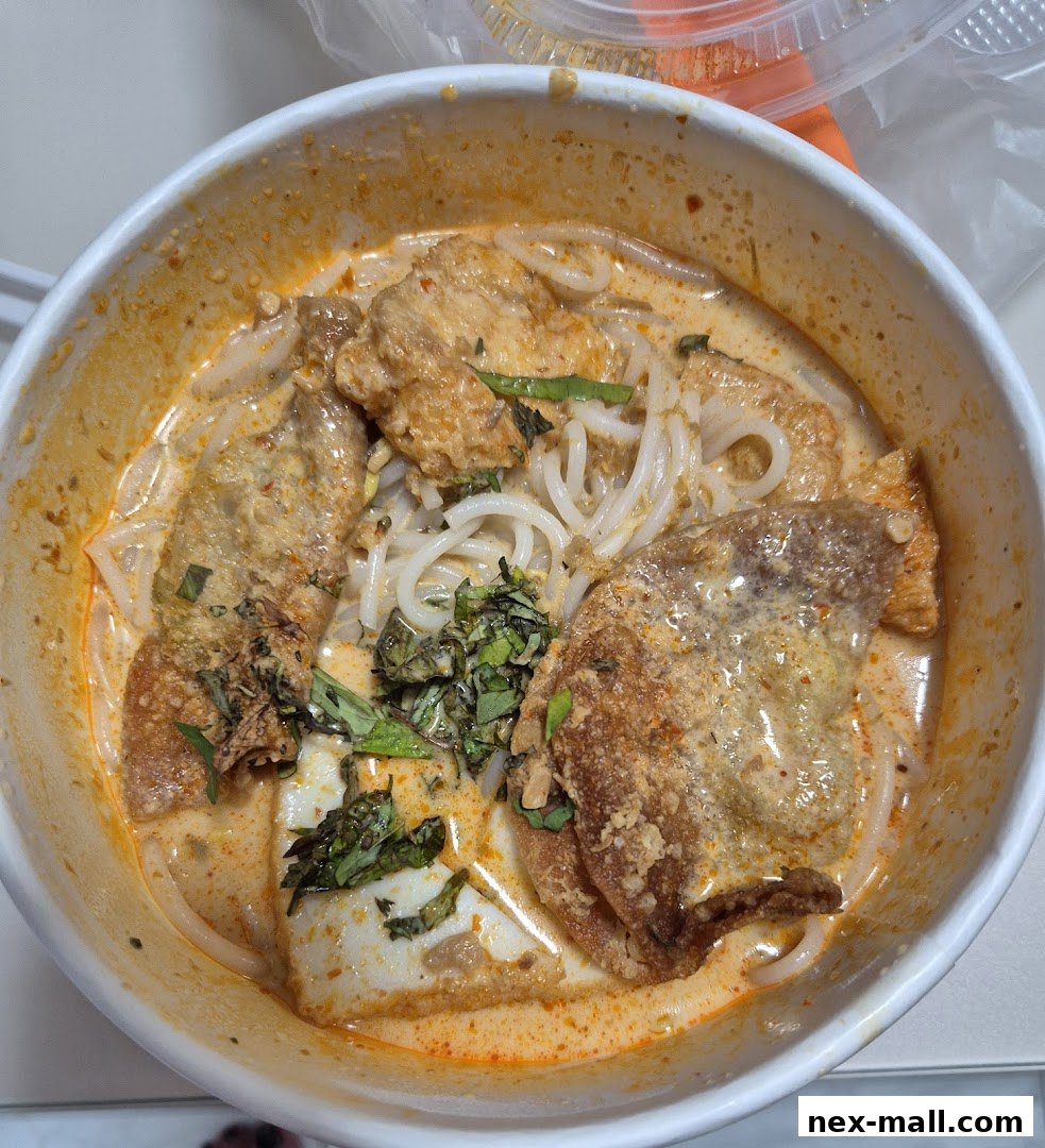 A close-up shot of a delicious bowl of Laksa with noodles, fish cakes, and fried tofu.