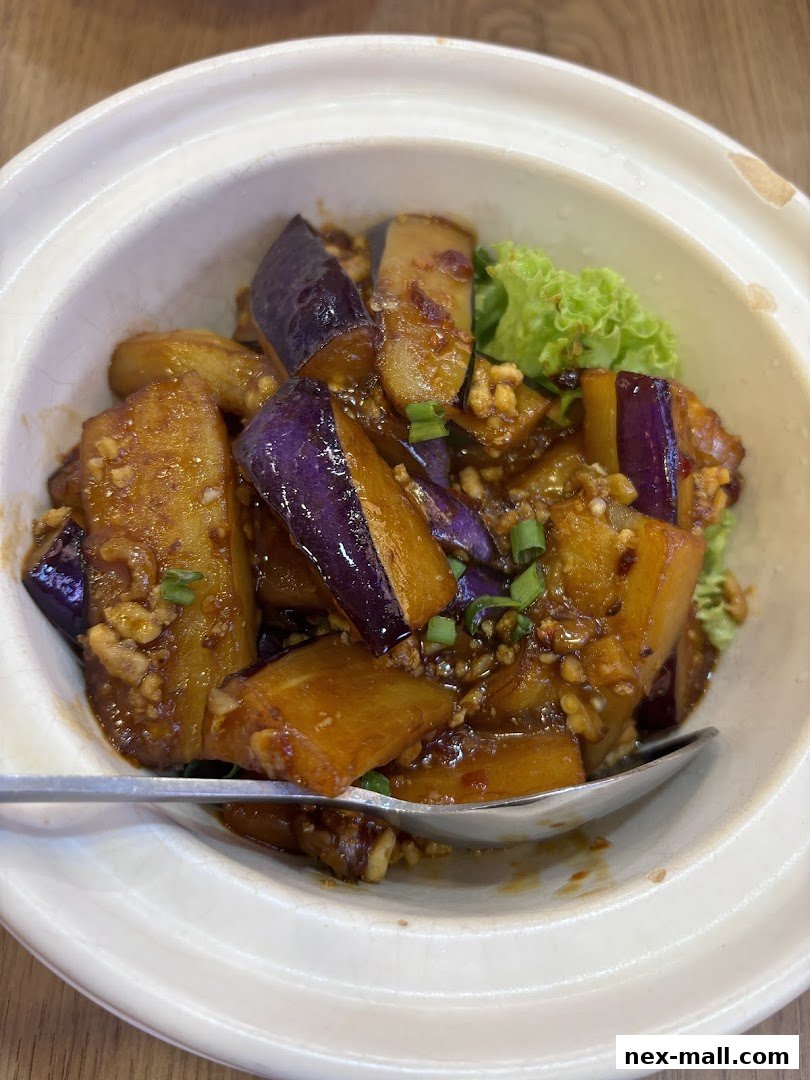 A close-up shot of a delicious dish of stir-fried eggplant with minced meat and a garnish of lettuce.