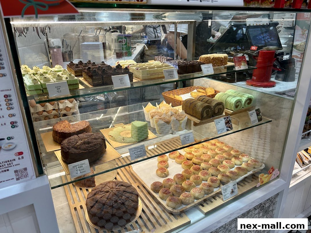 A display case filled with various cakes, pastries, and baked goods at Toast Box.