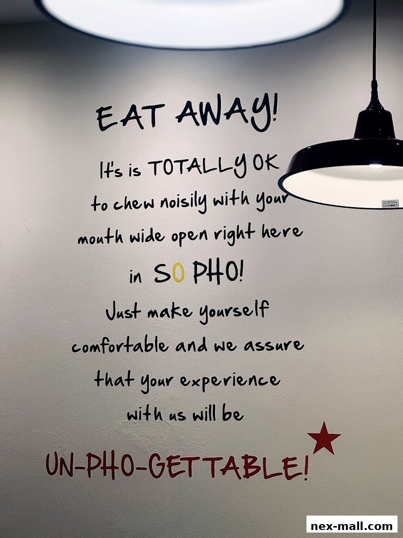A wall with a humorous quote about eating pho, with a pendant light overhead.