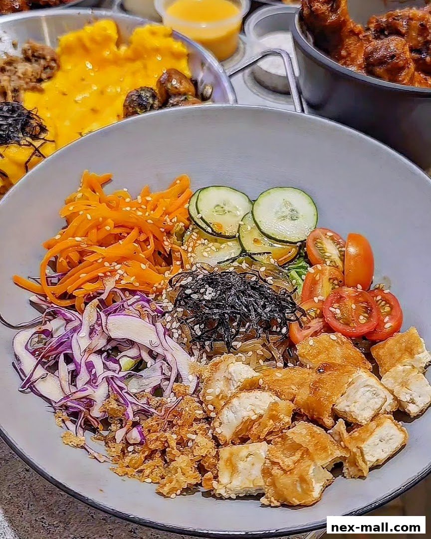 A close-up of a delicious Korean-inspired bowl with fried chicken, vegetables, and noodles.