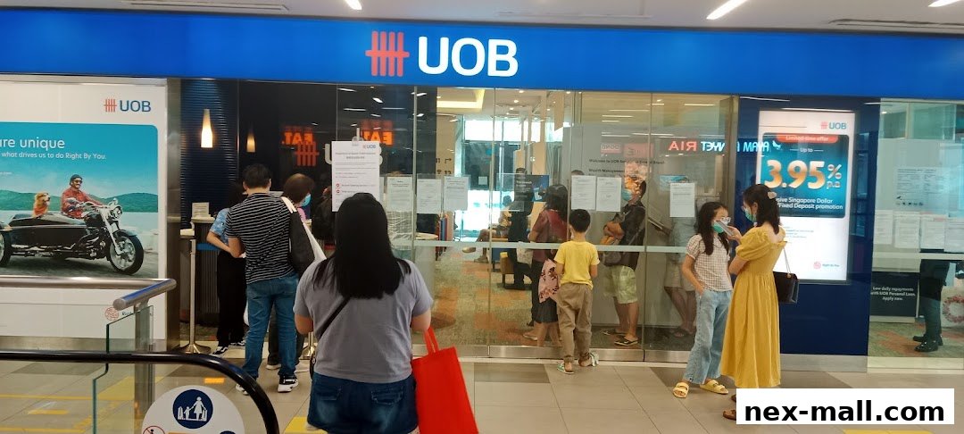 People queuing outside a UOB bank branch with promotional posters.