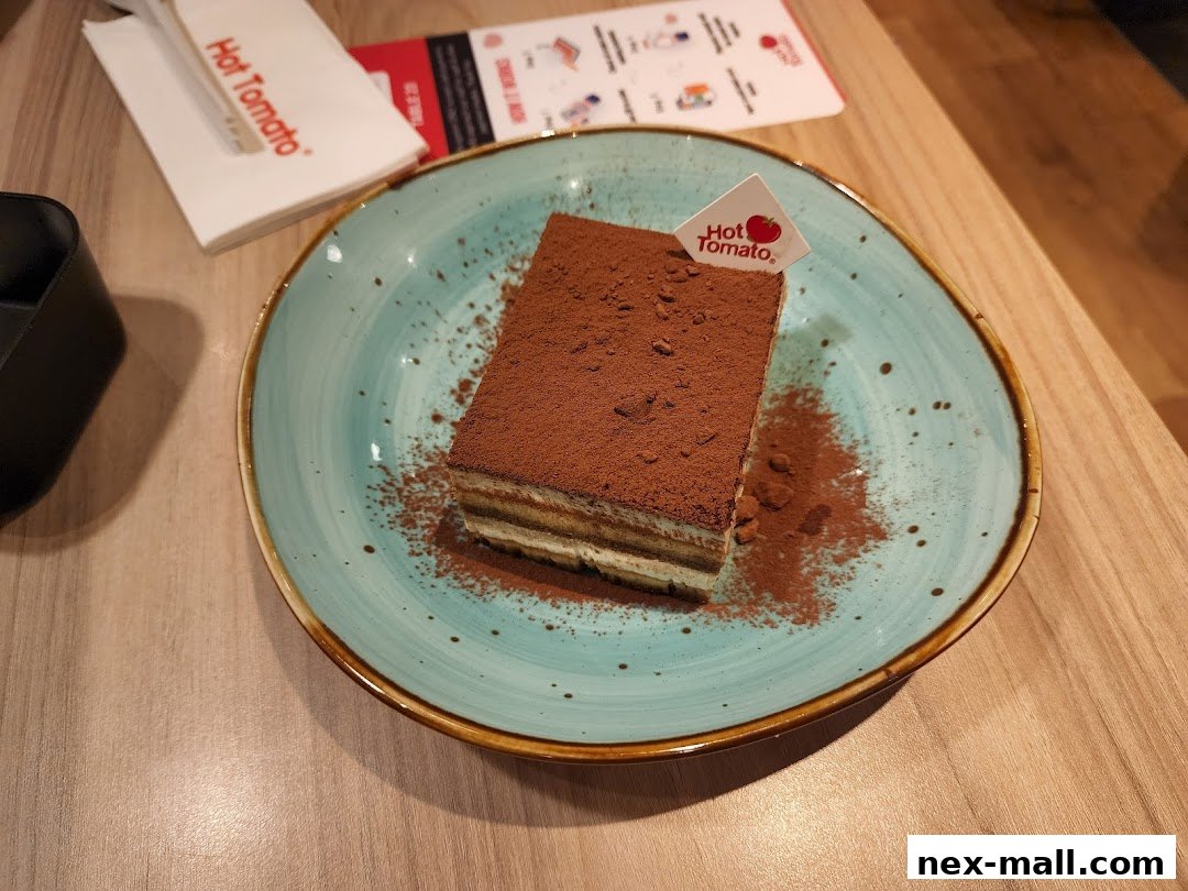 A slice of tiramisu cake dusted with cocoa powder on a teal plate.