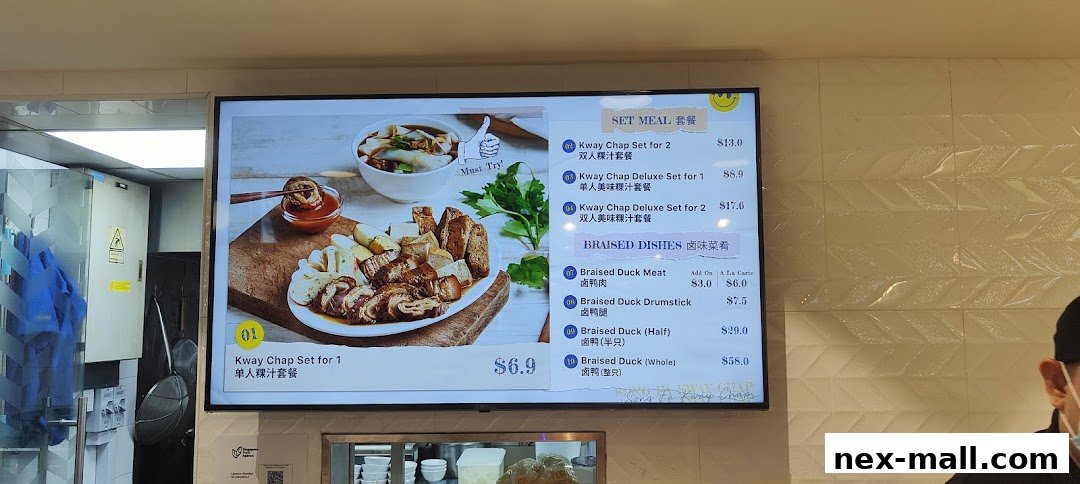 A digital menu board displaying Kway Chap sets and braised duck dishes with prices.