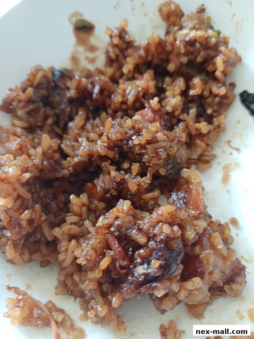 A close-up of a savory dish featuring sticky rice with visible pieces of meat and a glossy sauce.