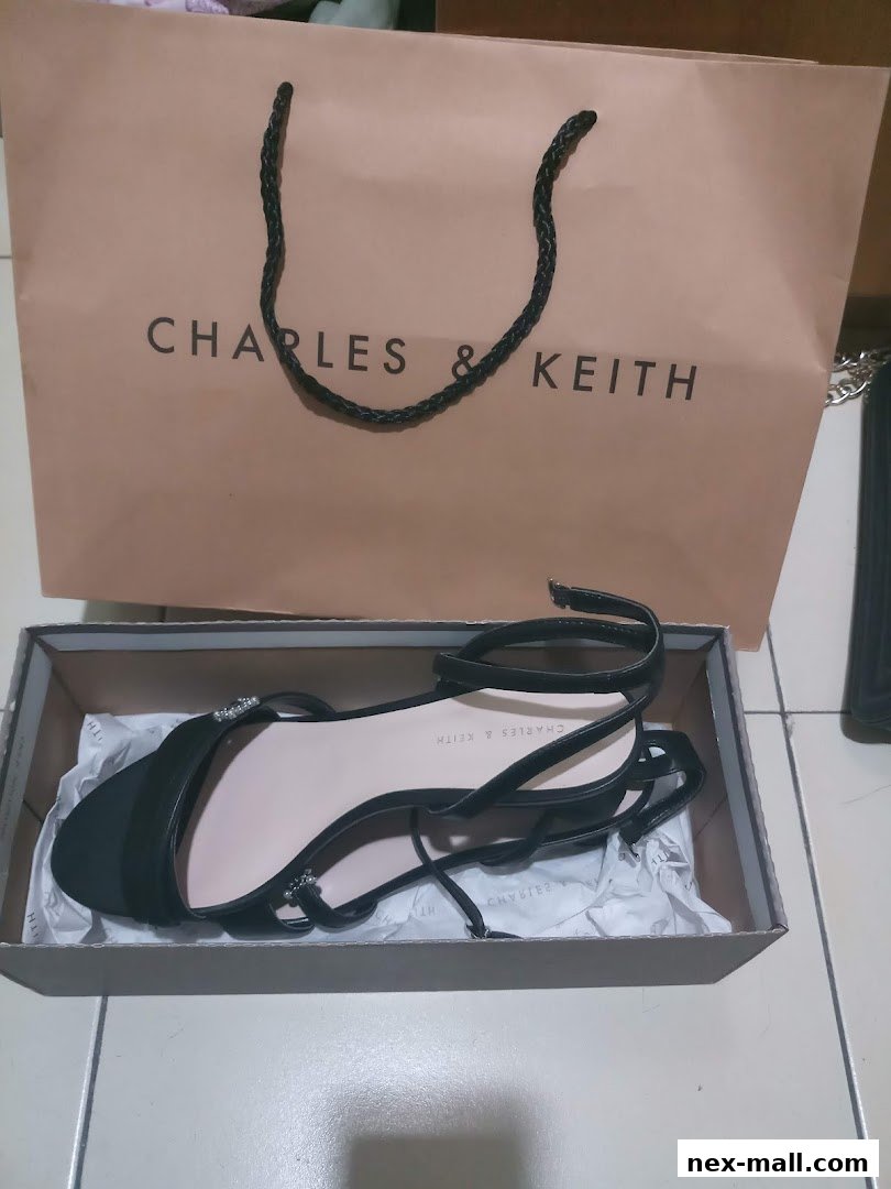 A pair of black Charles & Keith sandals in a box with a shopping bag.