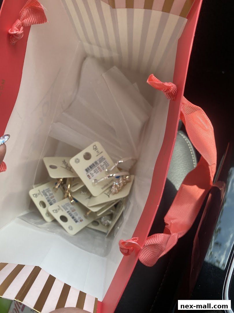 A pink shopping bag filled with various jewelry items on display cards.