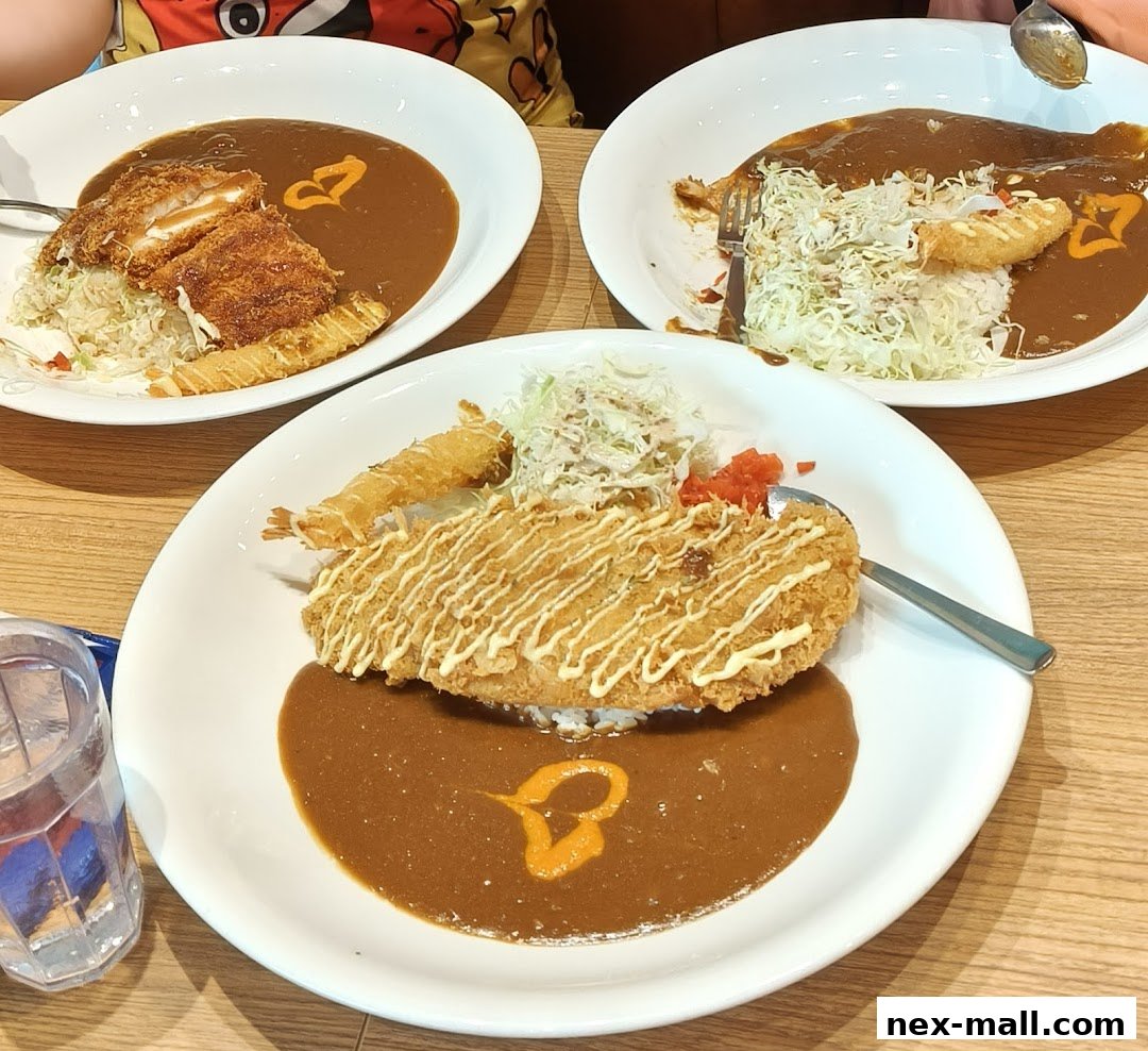 Three plates of Japanese curry with fried toppings and salad on a wooden table.