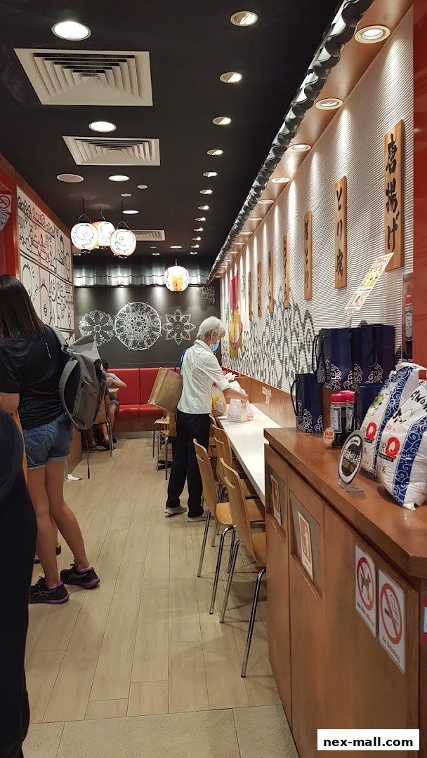 Customers are served at the counter of a Japanese restaurant with decorative elements on the walls.