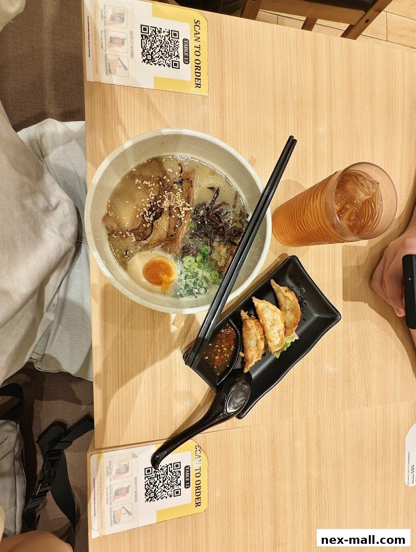 A table at Tokyo Shokudo with a bowl of ramen, gyoza, and a drink.