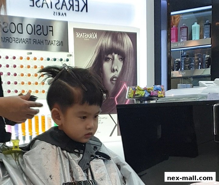 A young boy is getting a haircut at NK Hairworks, with Kérastase branding visible.