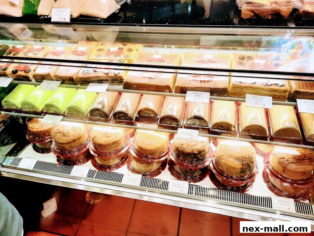 A display case filled with various cakes, rolls, and pastries, showcasing a wide selection of desserts.