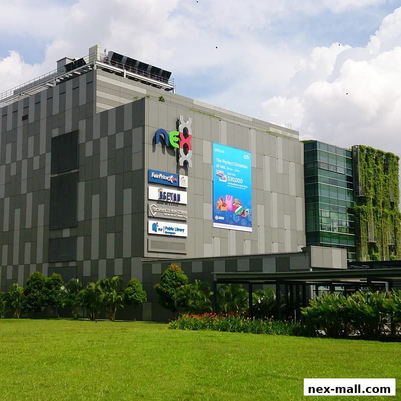 The exterior of the NEX shopping mall with various store signs and a green wall.
