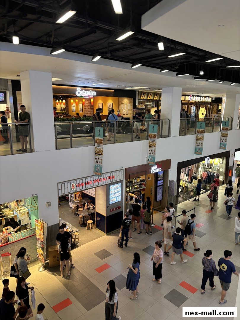 A busy shopping mall interior with various shops and people walking around.