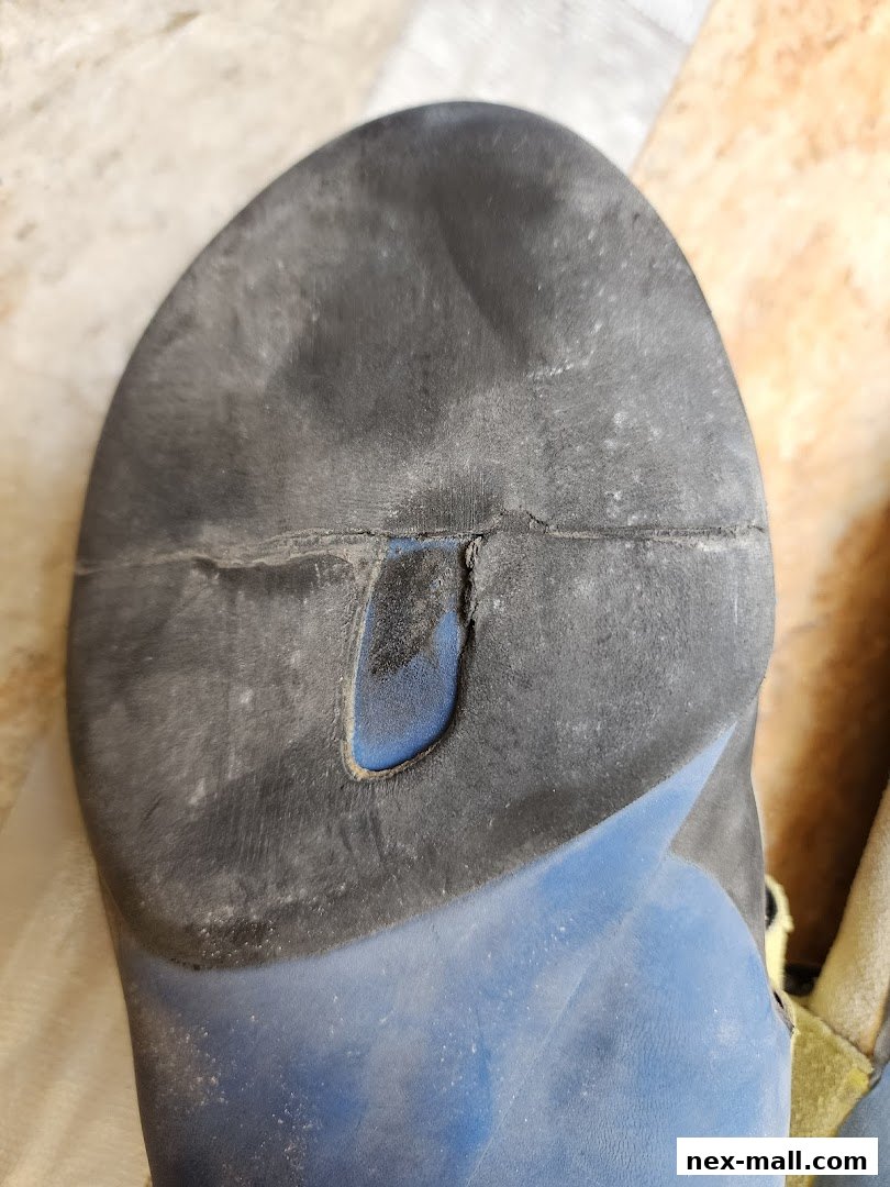 Close-up of the worn sole of a blue and black climbing shoe.