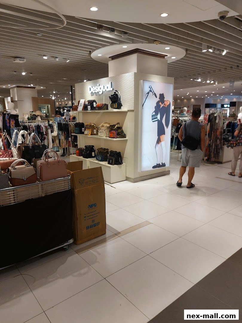 Interior view of a Desigual store showcasing bags and clothing with shoppers browsing.