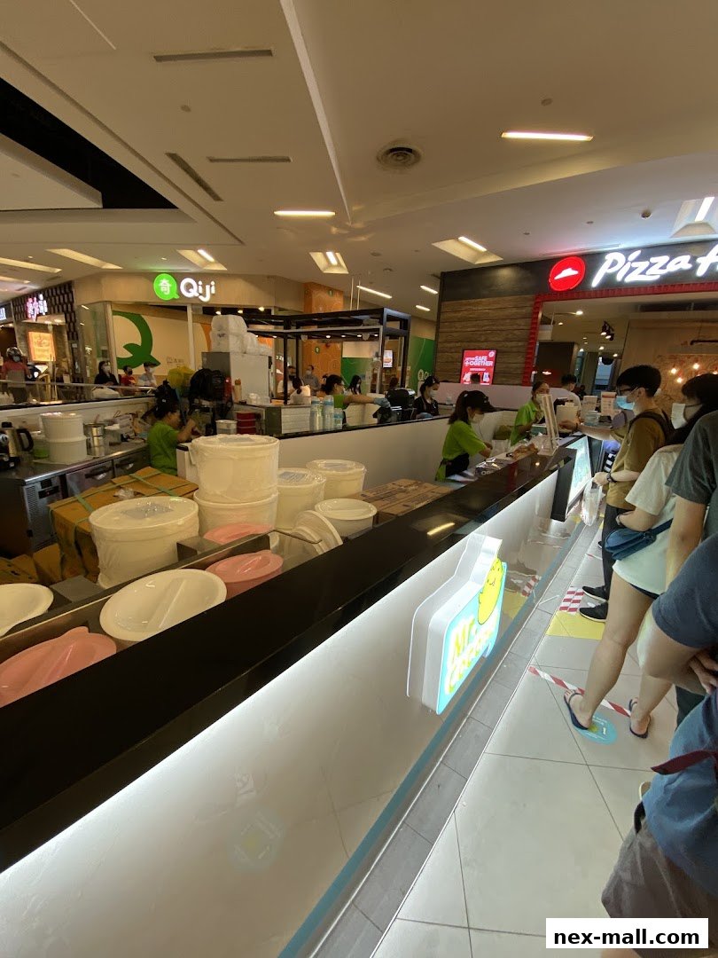 A busy food court with several shops, including Mr. Coconut and Pizza Hut, and customers queuing.
