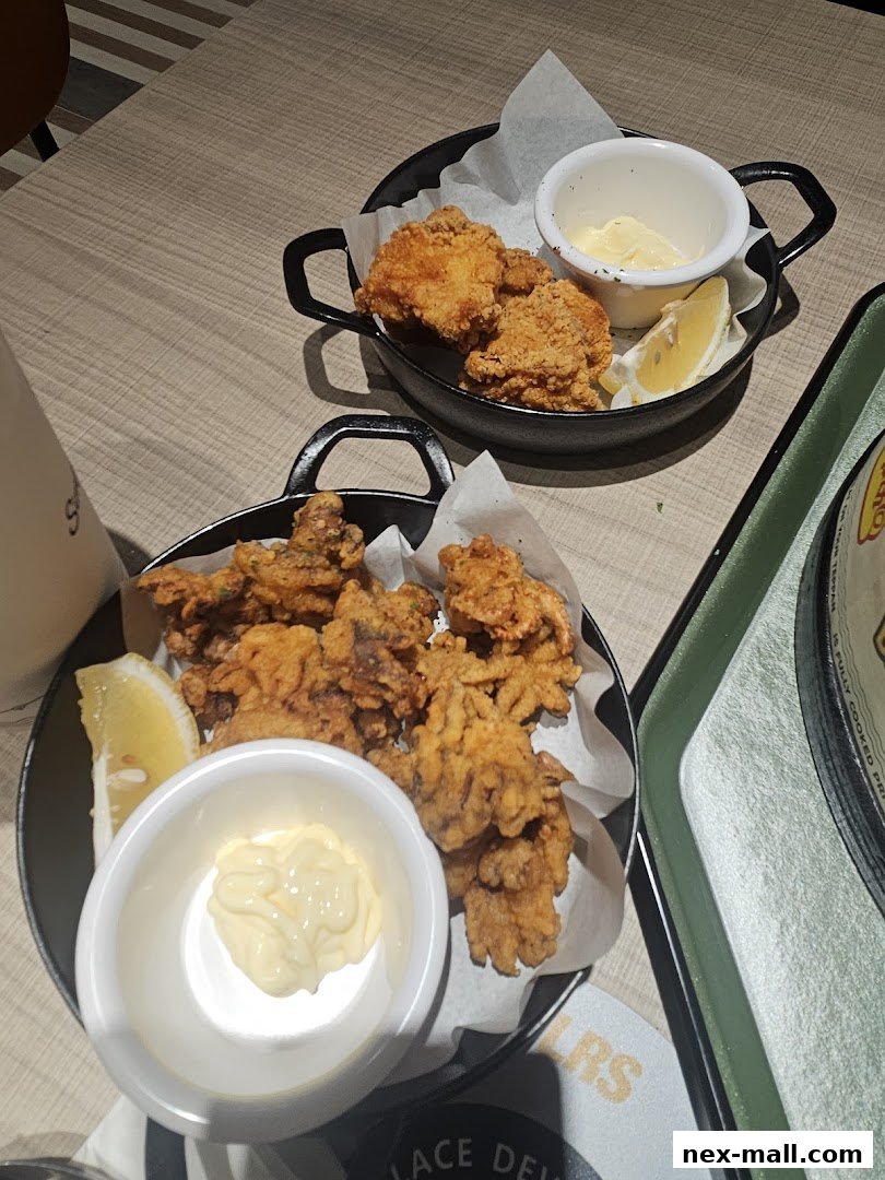Two servings of fried calamari and chicken with lemon wedges and dipping sauce.