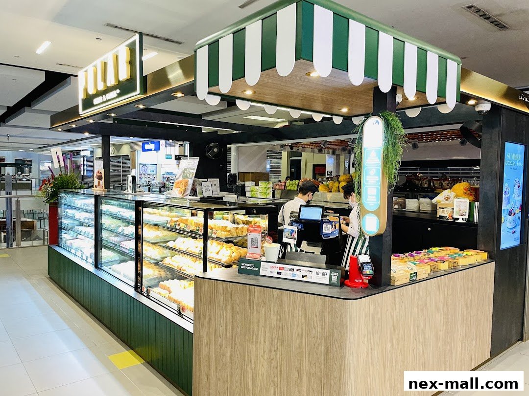 A brightly lit bakery counter displaying a variety of pastries and cakes, with staff serving customers.
