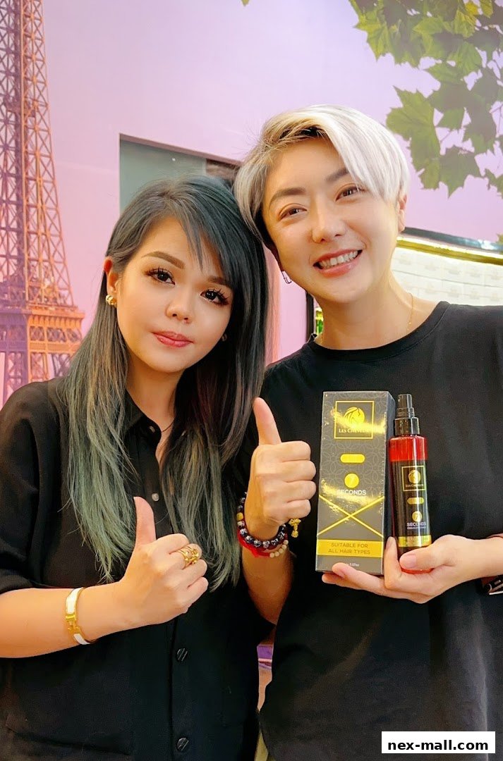 Two smiling individuals give thumbs up while holding a hair product from Mystique Hub.