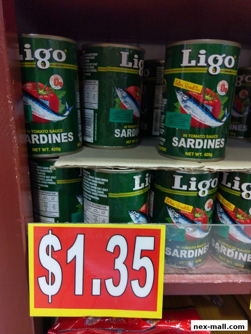 Cans of Ligo sardines in tomato sauce are displayed on a shelf with a price tag of $1.35.
