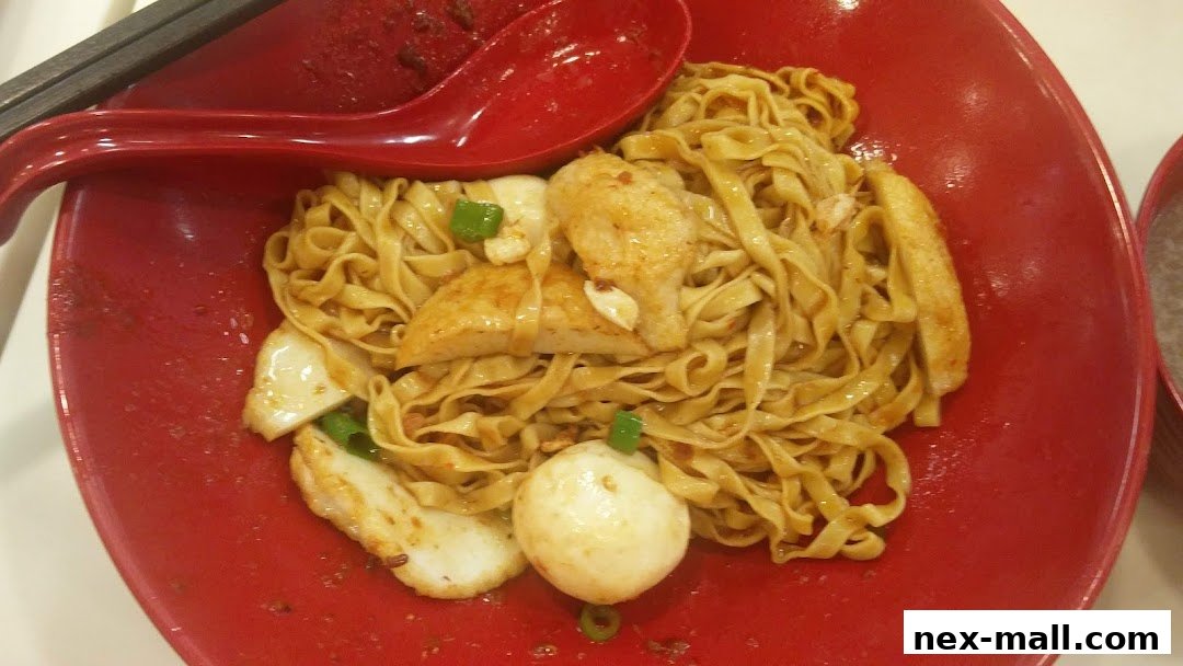 A close-up shot of a bowl of noodles with fish cakes and a spoon.