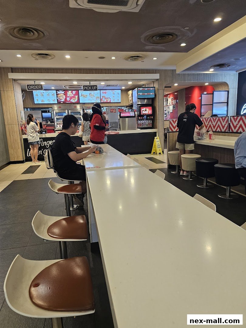 Interior view of a KFC restaurant with customers ordering and dining.