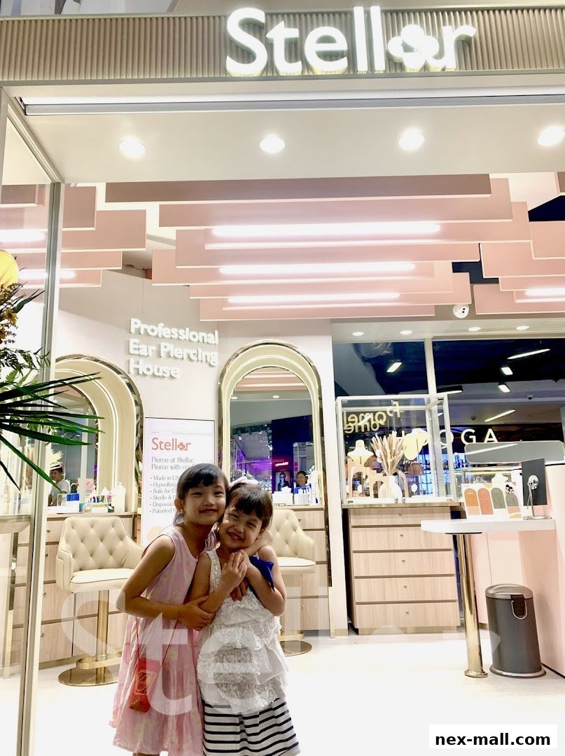 Two smiling girls in front of Stellar, a professional ear piercing house.