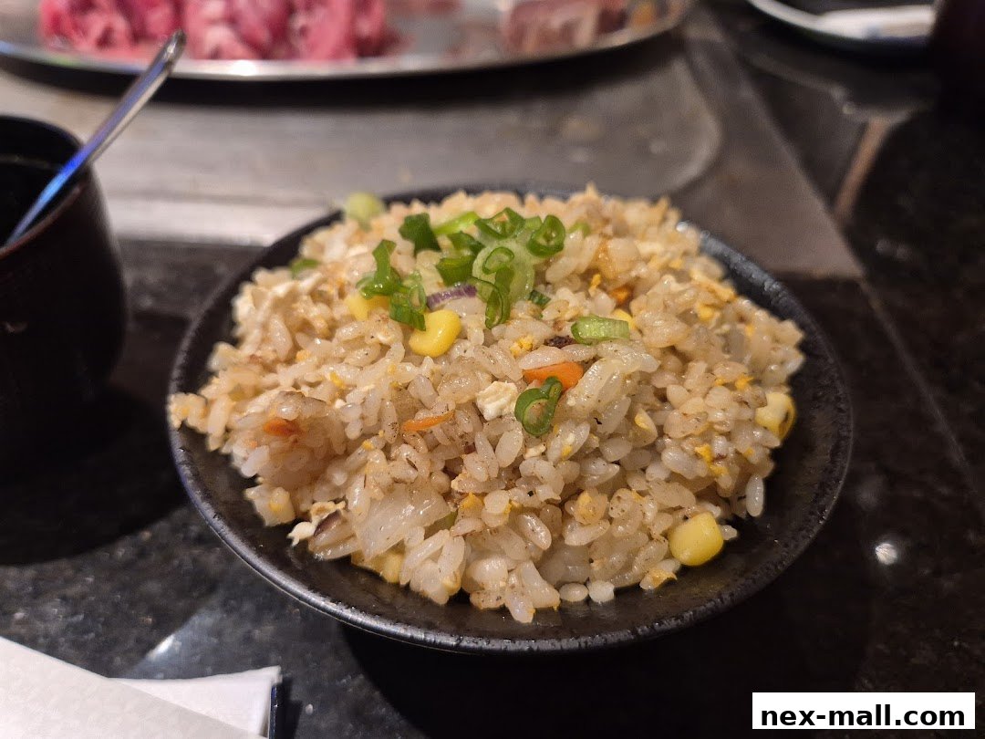 A close-up of a bowl of fried rice with corn and green onions.
