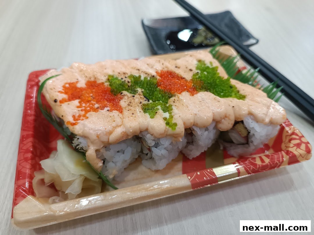 A close-up of a sushi roll topped with creamy sauce and roe, served with chopsticks and soy sauce.
