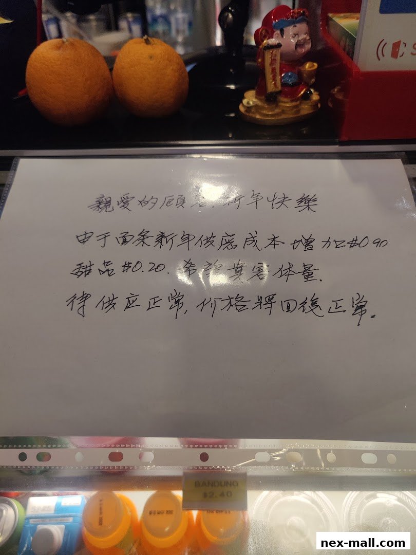 A handwritten notice about price adjustments due to increased costs, with oranges and a figurine in the background.
