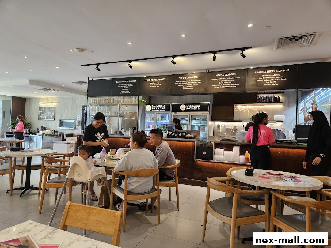 Diners enjoy meals at Go-Ang Pratunam Chicken Rice, with a menu displayed above the counter.