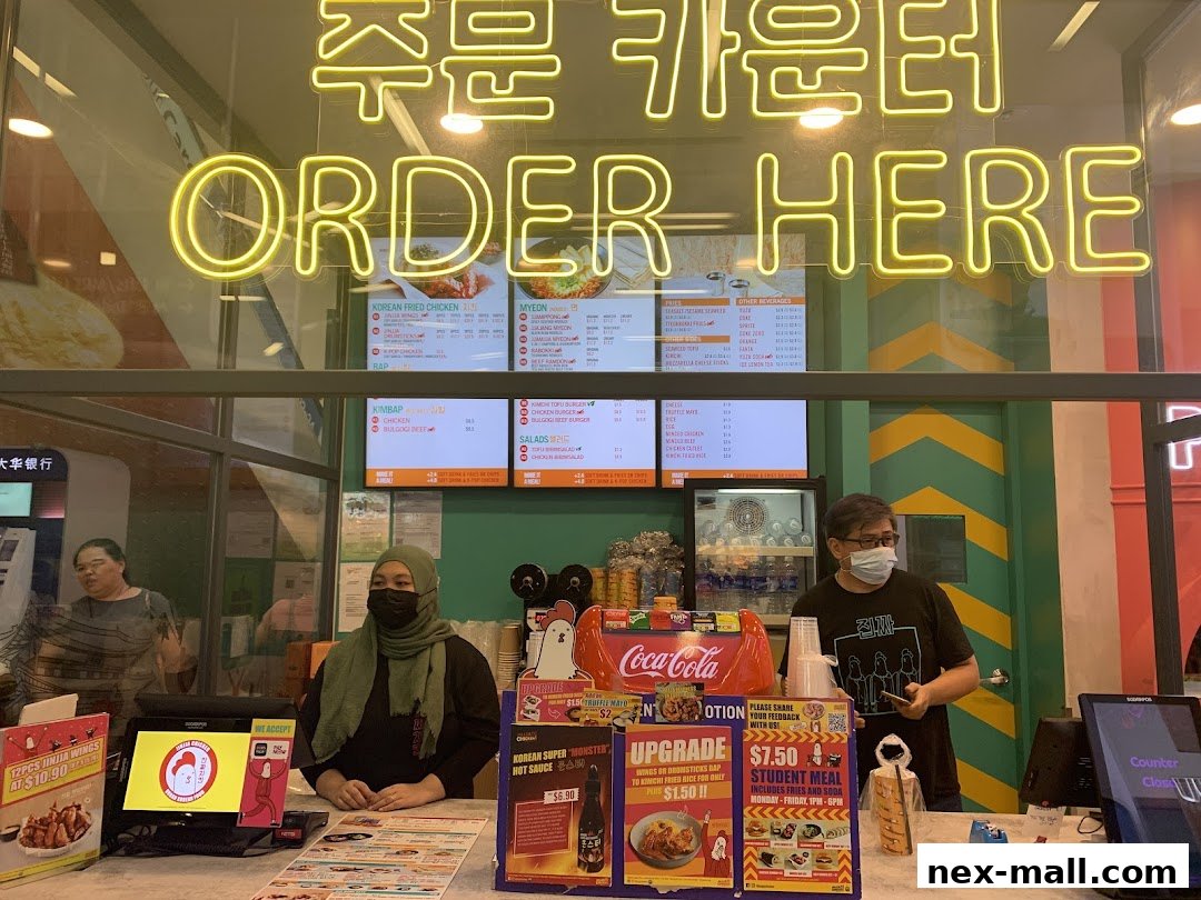 A view of the JINJJA Chicken counter with a menu board and staff.