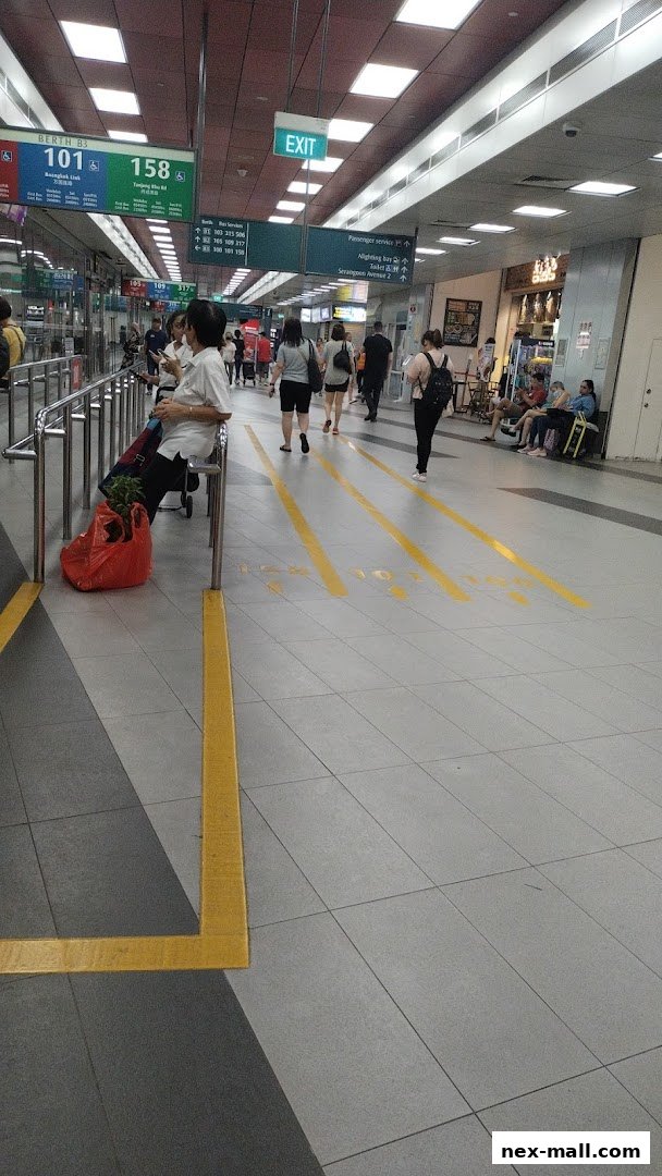 People walking in a well-lit indoor walkway with signage and shops visible.