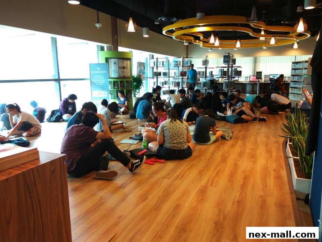 People sitting on the floor in a library, reading and using laptops.