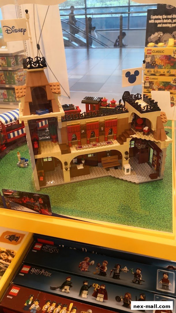 A detailed LEGO model of a building with Disney and Mickey Mouse flags, displayed in a store.