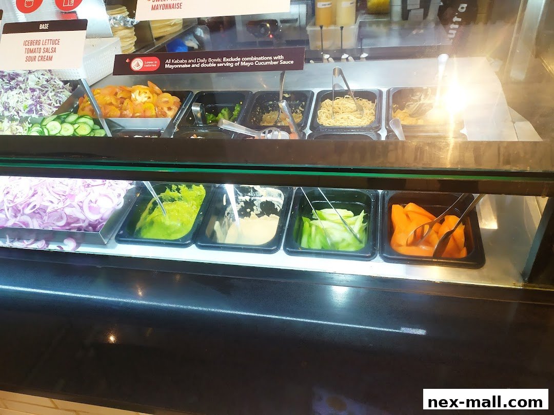 A display case filled with fresh ingredients for kebabs and bowls, including vegetables and sauces.