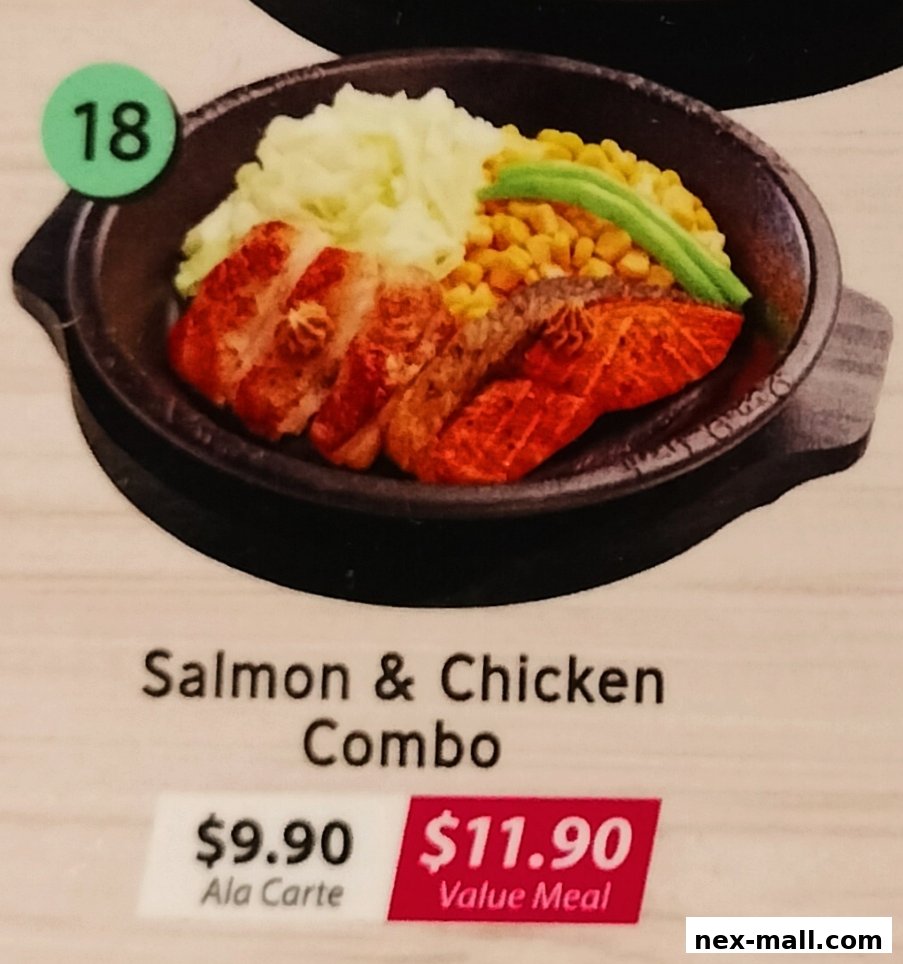 A sizzling hot plate featuring a salmon and chicken combo with mashed potatoes, corn, and green beans.