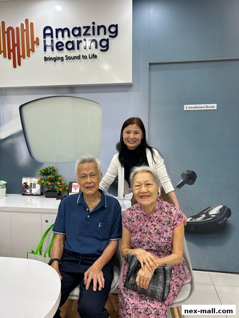 A smiling staff member stands behind a happy elderly couple at Amazing Hearing.