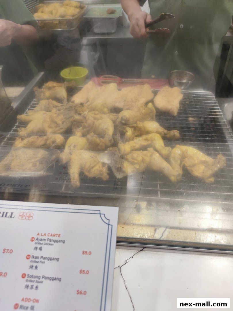 A display of grilled chicken and fish at a food stall with a menu visible.
