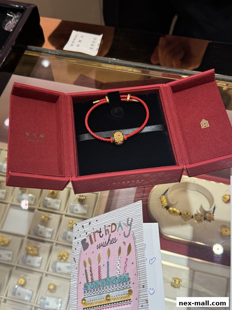 A red jewelry box with a gold and red bracelet, next to a birthday card.