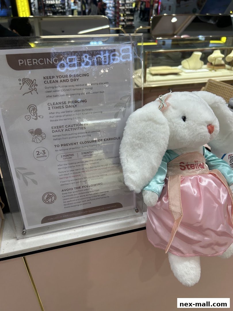 A sign detailing piercing aftercare instructions next to a plush bunny wearing a Stellar branded outfit.