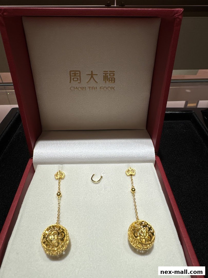 A pair of ornate gold drop earrings displayed in a red jewelry box.