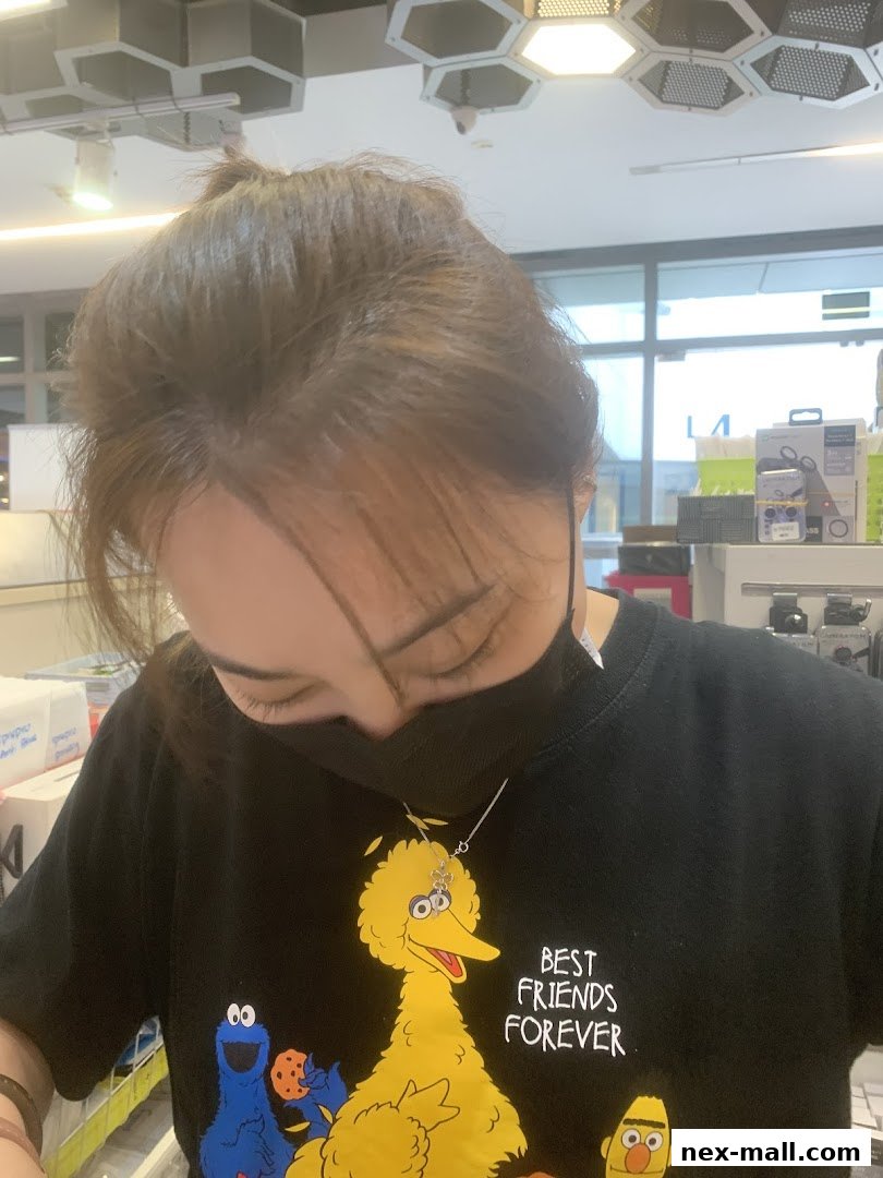 A person wearing a black t-shirt with Sesame Street characters and a face mask.