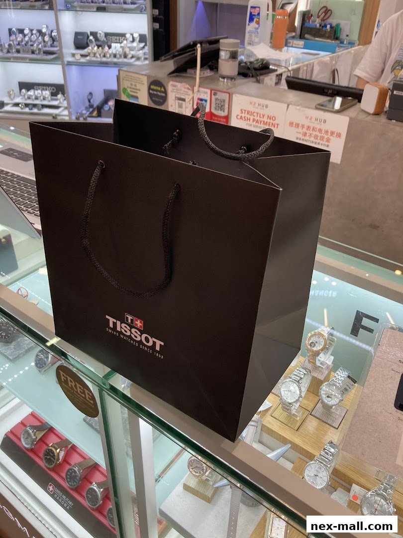 A Tissot shopping bag sits on a display counter in a watch shop, with watches visible in the background.