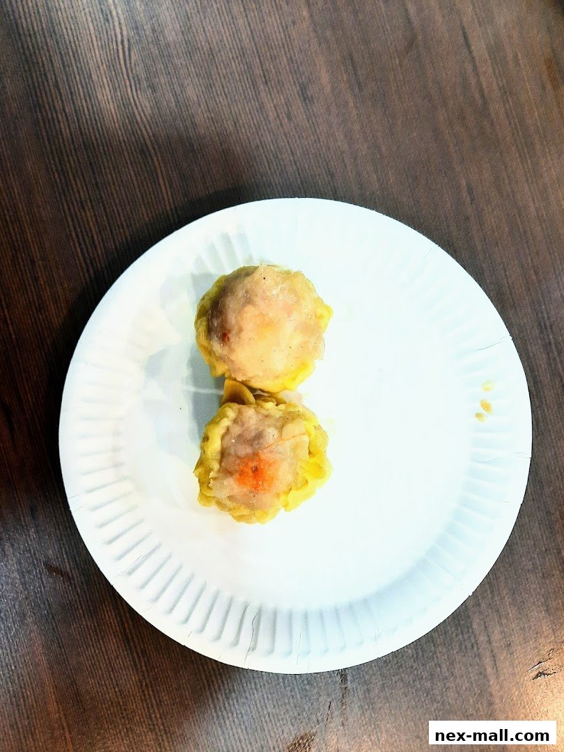 Two delicious dim sum dumplings served on a white paper plate.
