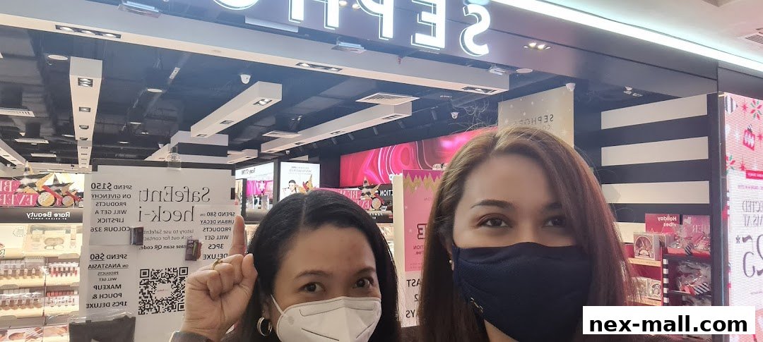 Two women in masks stand in front of a Sephora store with promotional signs.