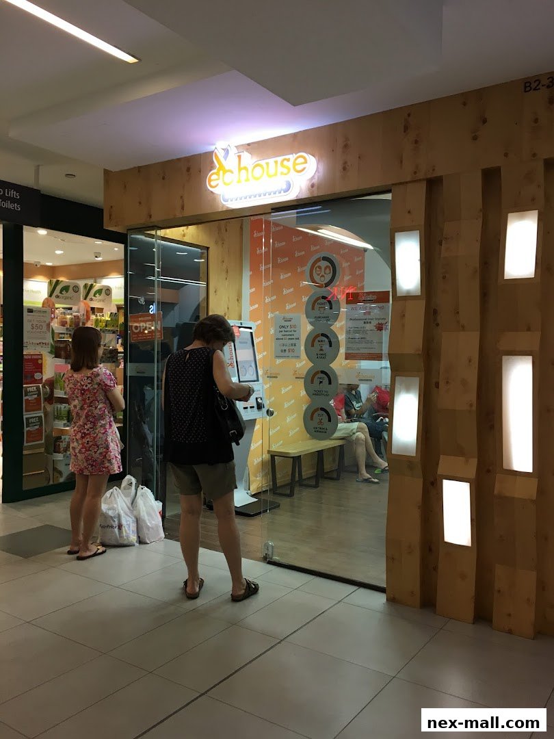 People interacting with a self-service kiosk outside a hair salon with a wooden facade.